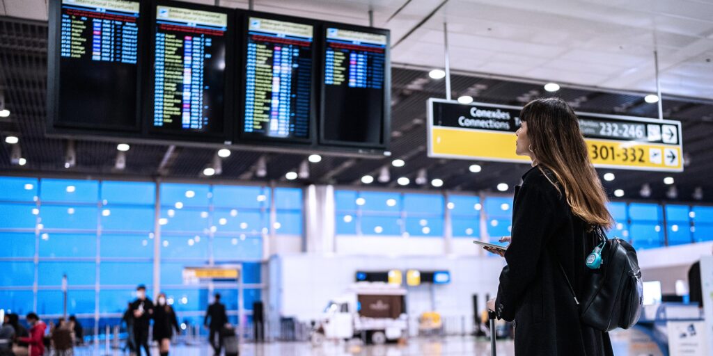 Viajera revisando vuelos en el aeropuerto antes de viajar a Roma