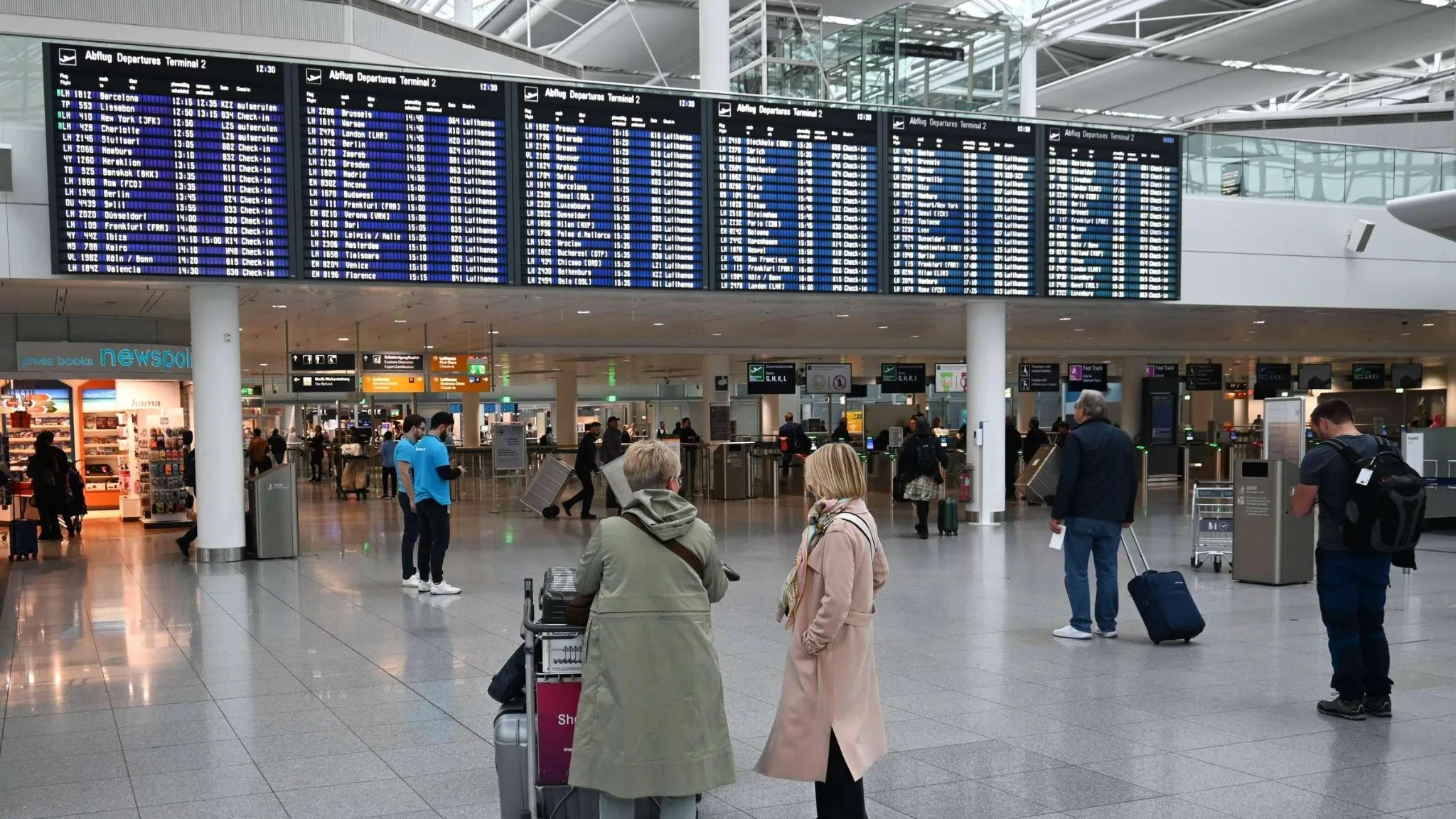 Viajeros bajo paneles de salidas en una terminal aeroportuaria
